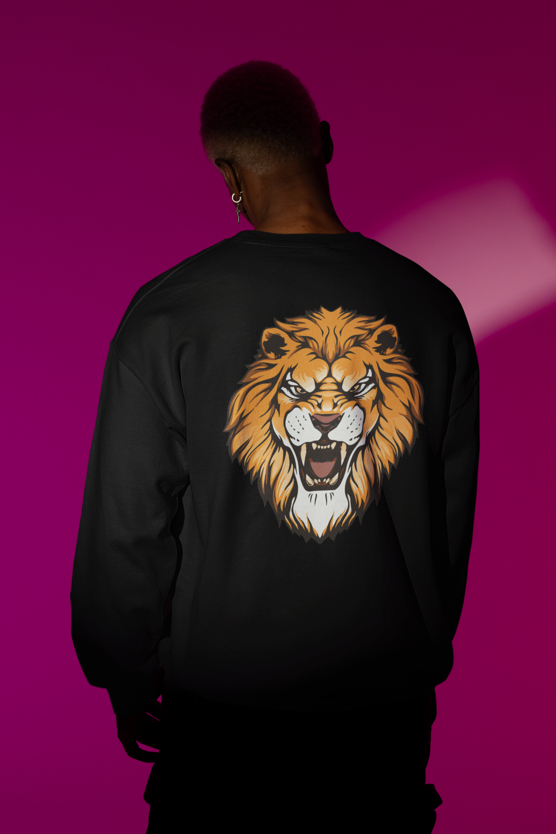Person wearing a black sweatshirt with a lion graphic on the back against a pink background