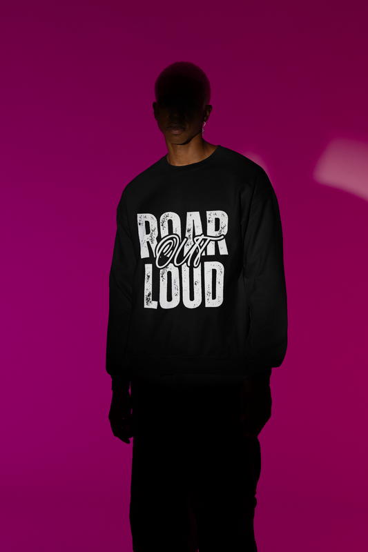 Person wearing a black sweatshirt with 'ROAR OUT LOUD' text on a pink background