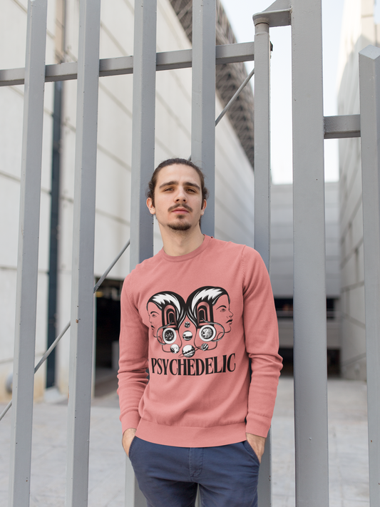 Man wearing a pink sweatshirt with a psychedelic graphic design and text, standing in front of a modern architectural structure.